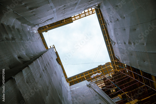 Building with scaffolding and a large piece of tarp covering the top. The tarp is being used to protect the building from the elements