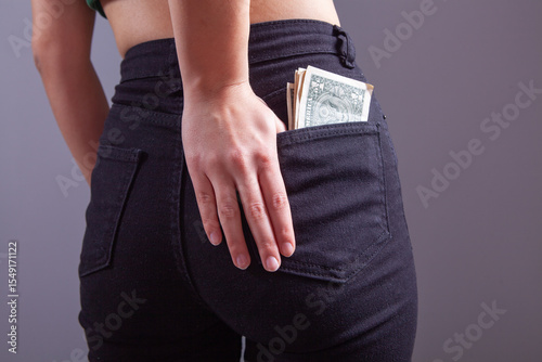 woman holds a black wallet with dollars in her hand.