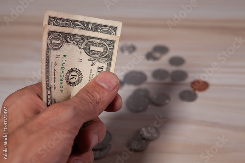 hand holding a wooden coin with a dollar bill.