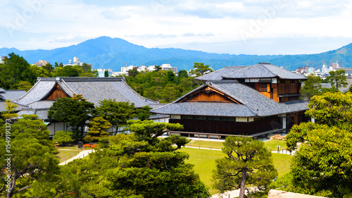 Traditional Rooftops of Nijo Castle with Kyoto Skyline and Mountains