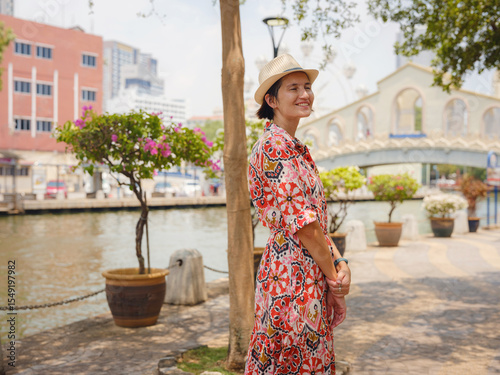 Young woman in ethnic dress and hat exploring the vibrant streets of Malacca, Malaysia. A blend of cultural heritage, colorful architecture, and tropical charm. Perfect travel and lifestyle moments.