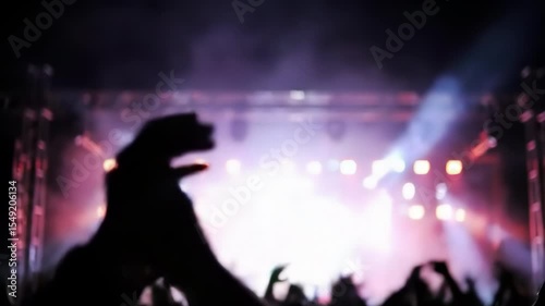 Blurred crowd silhouettes clap at night concert, lights and energy create a festive atmosphere – celebration, music, unity, entertainment concept
