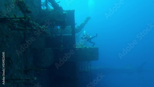 Wreckship of superstructure on Salem Express ferry, scuba diver filming wreck on the blue water background, Slow motion of diver swims in blue depths examines at sunken ship
