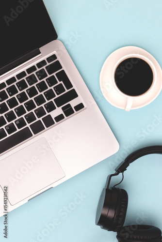 Headphones, cup of black coffee and laptop on a blue background. Business concept.