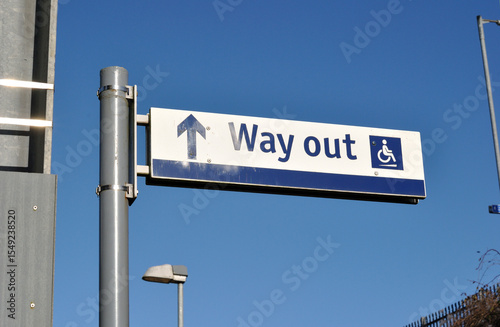 Steel Pole with 'Way Out' Sign at Railway Station seen against Blue Sky 
