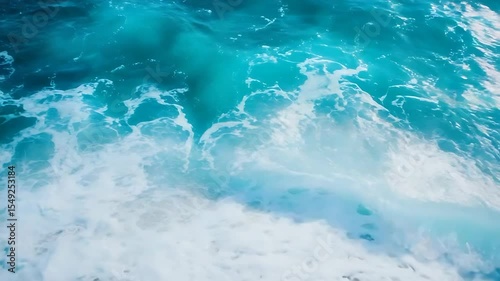 Vibrant turquoise ocean waves crashing onto a sandy beach under a clear blue sky, creating a serene atmosphere