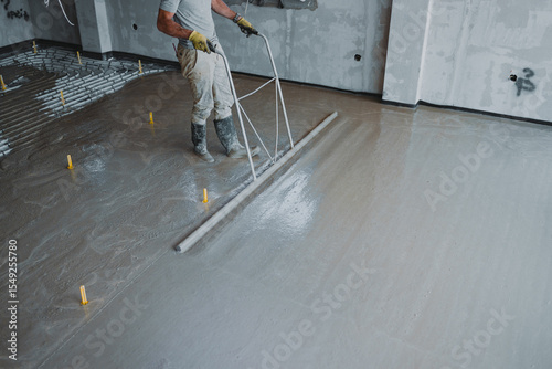 Construction worker leveling concrete surface flooring with trowel