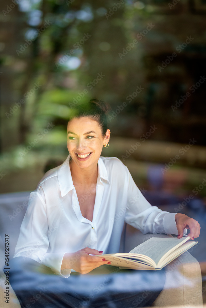 Obraz premium Attractive brunette haired woman relaxing in her cozy home, shot through a window