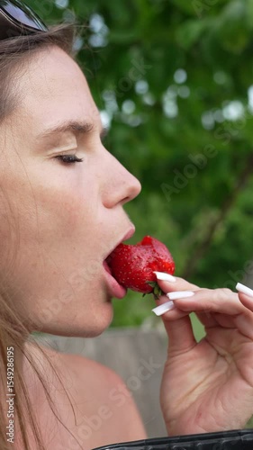 Woman Eating Strawberry outdoors enjoying fresh fruit