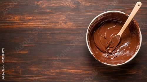 A deliciously inviting bowl of melted chocolate set against a rustic wooden background, ideal for evoking cravings and the simple joy of indulgent treats.