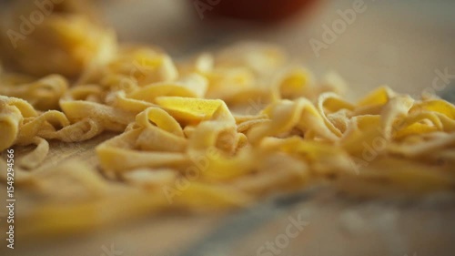 Delicate strands of freshly made pasta lay scattered on a wooden countertop, capturing the essence of Italian cuisine. This moment occurs in a kitchen, emphasizing homemade cooking