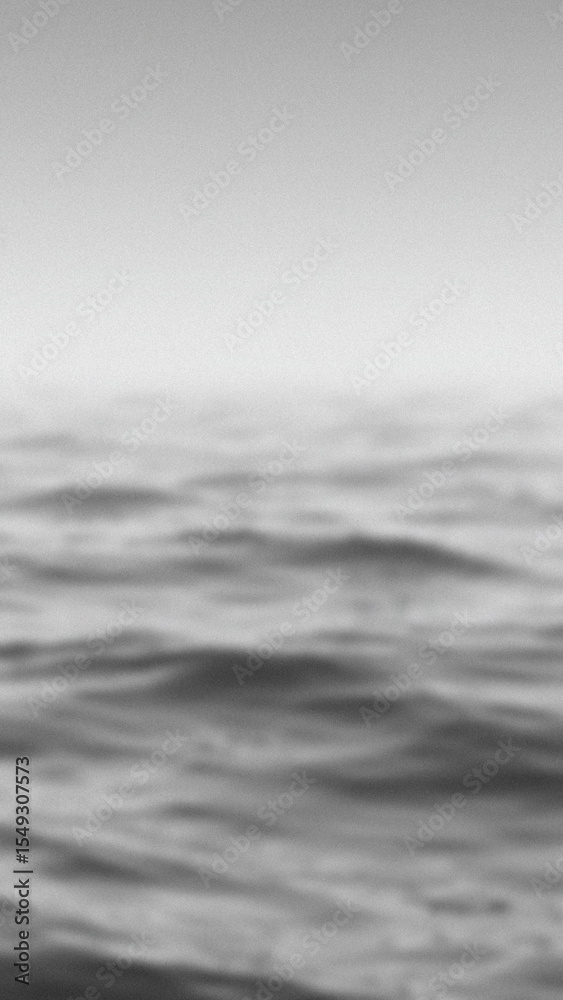 Fototapeta premium Blurred monochromatic view of water waves under a bright overcast sky creating a textured abstract backdrop with smooth