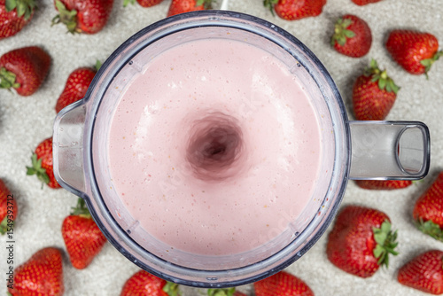 The process of making a strawberry milkshake, whisking all the ingredients in a blender.