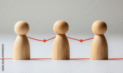 Three wooden figurines linked by red strings
