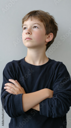 Pensive, thoughtful young boy with serious expression looking up. caucasian child portrait capturing moments of deep contemplation and determined ambition for future