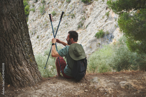 Man Relaxing with Hiking Poles Outdoors in Scenic Mountain Environment