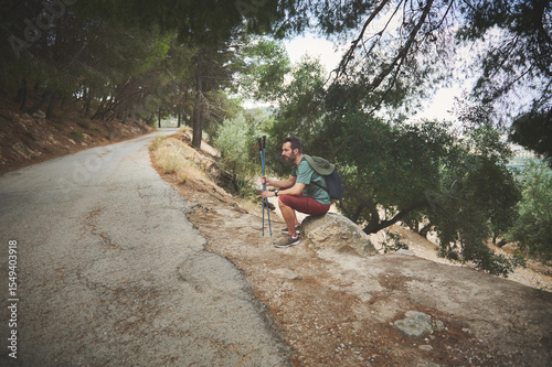 Hiker Resting on Mountain Path Surrounded by Scenic Forest