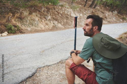 Hiker Pausing Along a Nature Trail Surrounded by Scenic Rocky Terrain and Trees