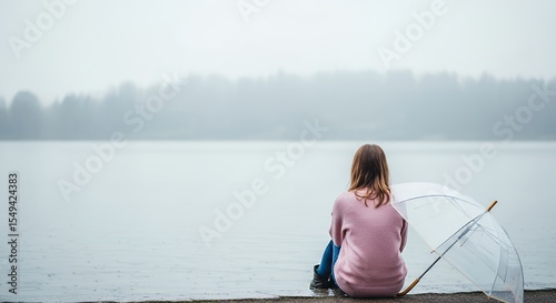 Young Woman Sitting by Lake with Umbrella on Rainy Day