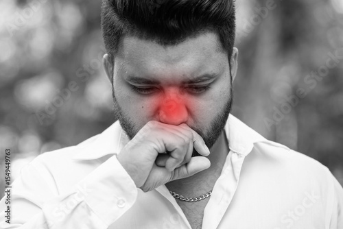 Unwell South Asian young adult man having cold, flu with allergic runny nose, nasal viral infection, dust allergy, air pollution, bad smell, stinky pungent smell, with dangerous red alert effect