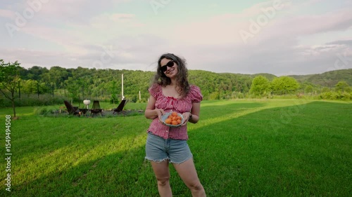 young curly woman holding bowl of freshly picked apricots from the garden. Summer garden. Slow life and eco conscious concept 