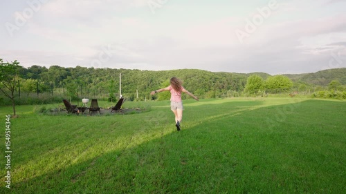 happy millennial woman enjoying the sunset outside on her  countryside property with a freshly mowed lawn 