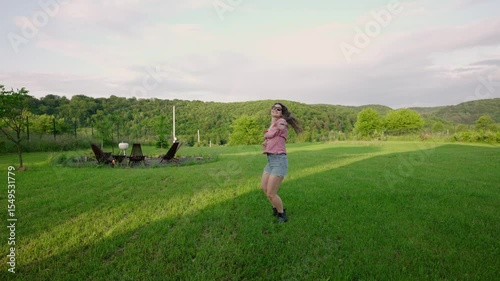happy millennial woman enjoying the sunset outside on her  countryside property with a freshly mowed lawn 