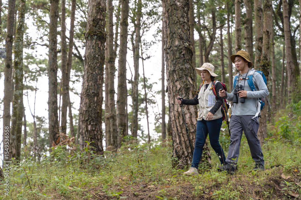 Obraz premium Asian male bird watcher and female trekker trekking in national forest