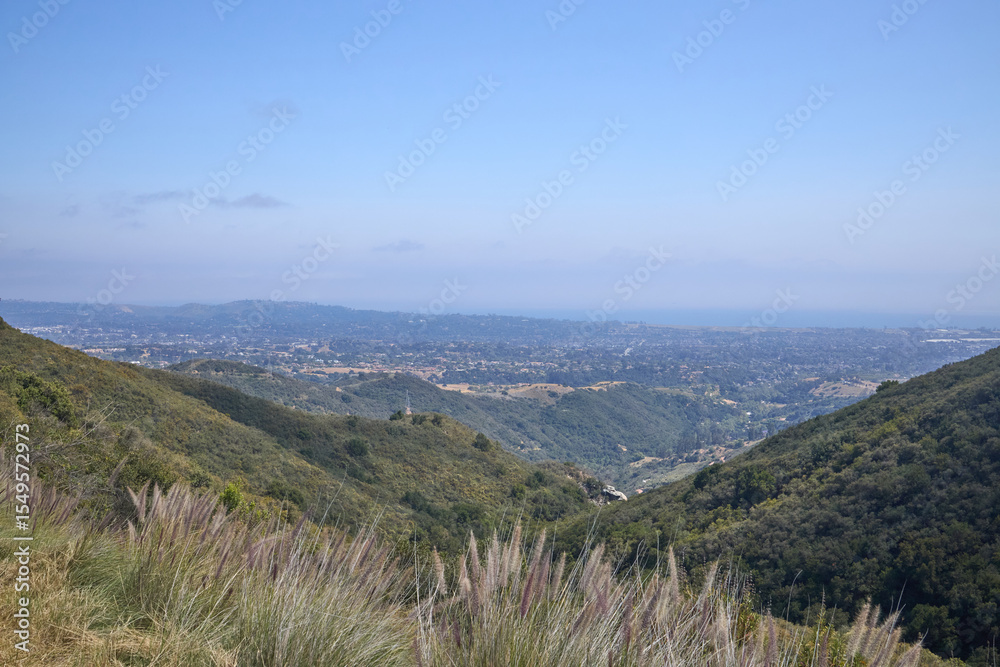 Fototapeta premium Mountain Valley Overlook with Grassy Foreground and Distant Hills 