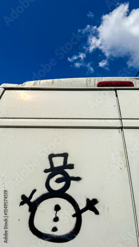 Graffiti snowman with inexplicable question mark, on van under azure sky, evokes quirky Festivus vibes, street art oddity