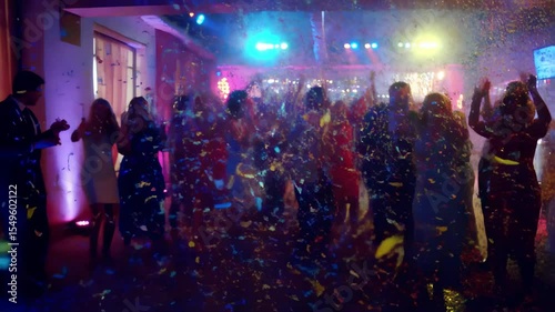 Colorful confetti falling on dancing people at party