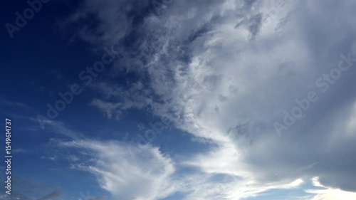 Time-lapse of white clouds and gathering storm clouds in a blue sky; fluffy moving clouds and dispersing