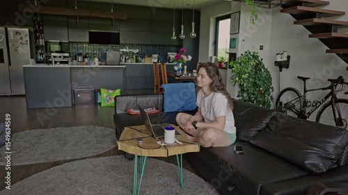 millennial woman working from home in her pajamas in the light and spacious living room. Remote jobs and digital nomad concept