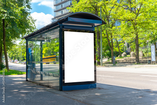 Blank bus stop mockup in sunny urban environment with green trees, ideal for outdoor advertising or city branding campaigns