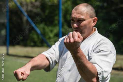 Man in white karate uniform practicing martial arts on a sports field.