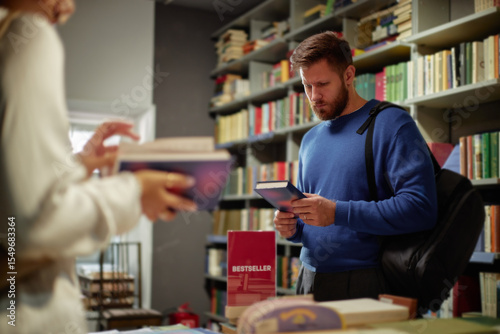 Quadro su tela Caucasian young adult man browsing books in bookstore, holding book and reading