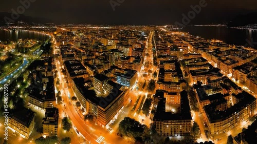 Night Skyline: Aerial view of a sprawling cityscape at night, illuminated by a network of lights, with a dark sky and distant body of water.