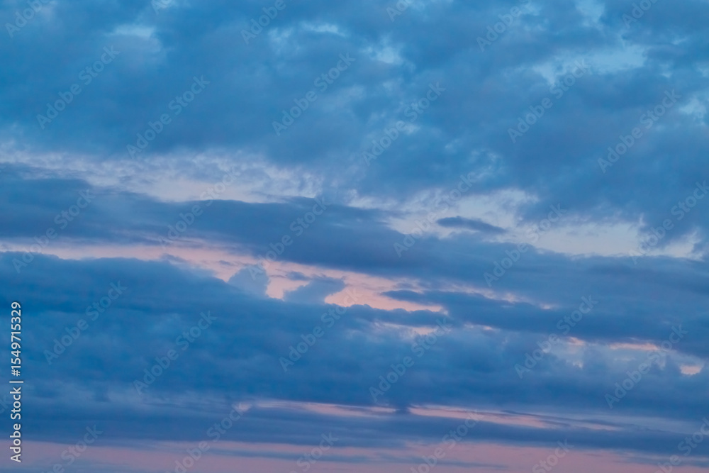 Obraz premium Clouds in sunset reflections: a gradient from magenta to lilac. Calm clouds tinted with rich evening tones convey an atmosphere of coziness and tranquility.