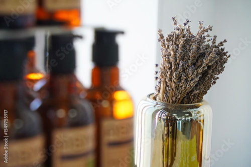 Lavender flowers with natural hair care products in background. Organic beauty concept with shampoo, conditioner, and herbal ingredients. Spa, wellness, eco-friendly lifestyle.