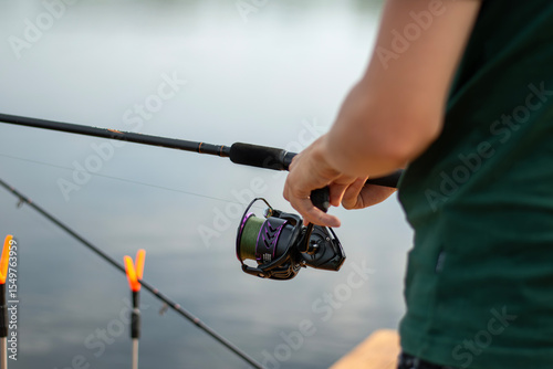 Fisherman hands holding fishing rod and reel close up. Professional tackle for catching predatory fish.