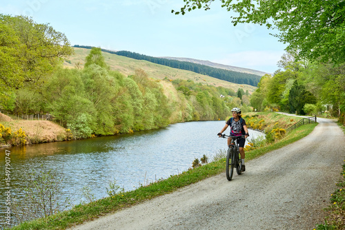 active senior woman riding her electric mountain bike along the Caledonian Canal near Fort William in Scotland, UK