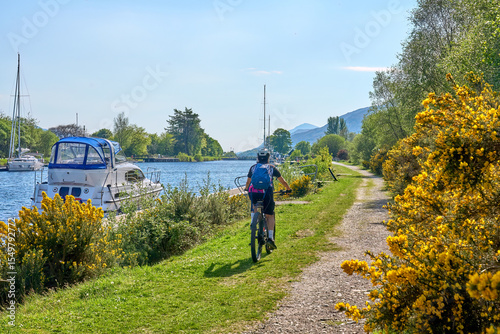 active senior woman riding her electric mountain bike along the Caledonian Canal near Fort William in Scotland, UK