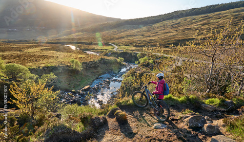 active woman riding her electric mountain bike along the awesome fairy pools on the Isle of Skye in Scotland, UK