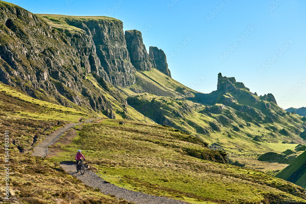 Fototapeta premium active woman riding her electric mountain bike in the awesome Quiraing mountains on the Isle of Skye in Scotland, UK
