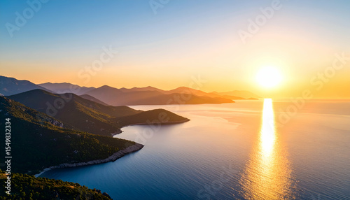 Sunrise over a calm sea with mountains in the background casting light.