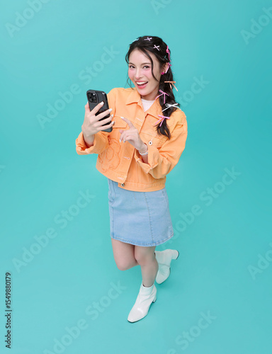 Top view Happy smiling young asian woman using mobile phone isolated on blue background. teen social media communication online.