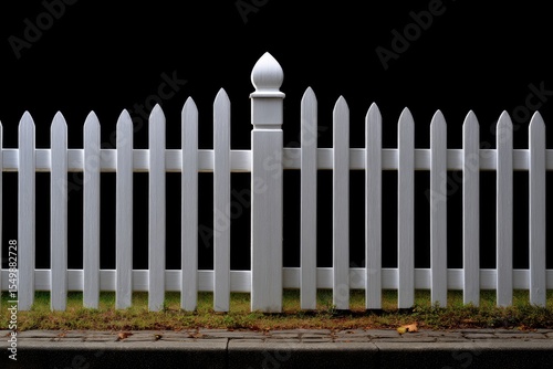 White picket fence with a decorative post on a black background and grass below