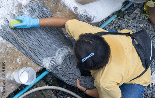 A girl washes the head of a spin mop on concrete