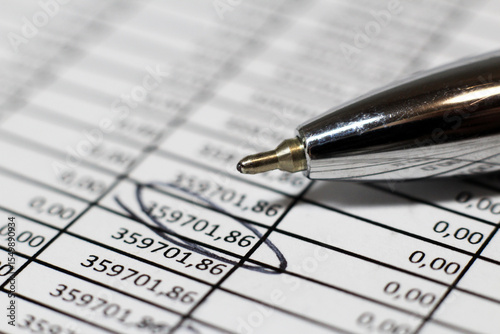 Pen and accounting report, numbers on paper.