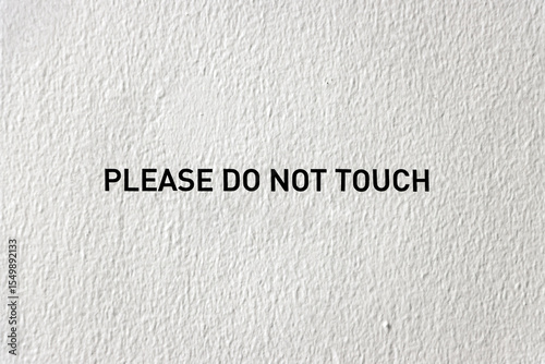 Minimalist black text warning sign indicating 'PLEASE DO NOT TOUCH' displayed on a textured wall surface.